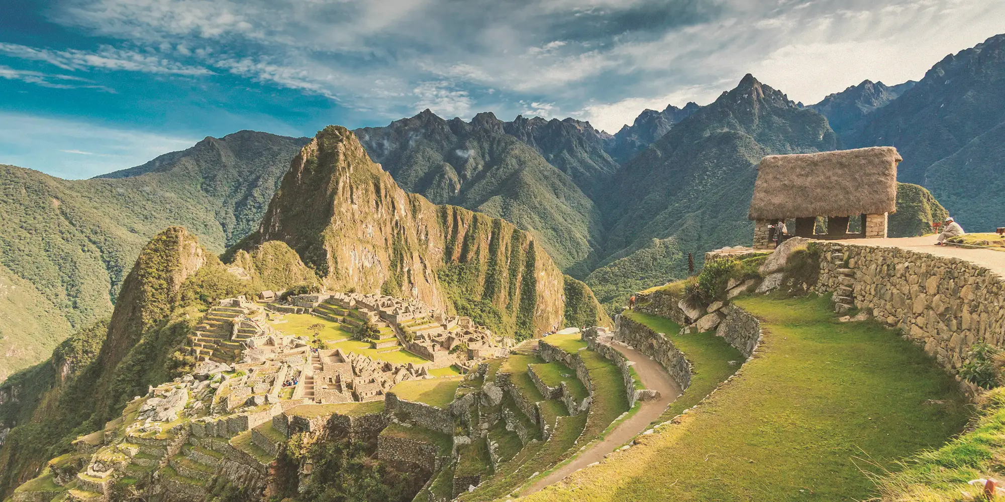 Traveler in a poncho and hat looking over Machu Picchu